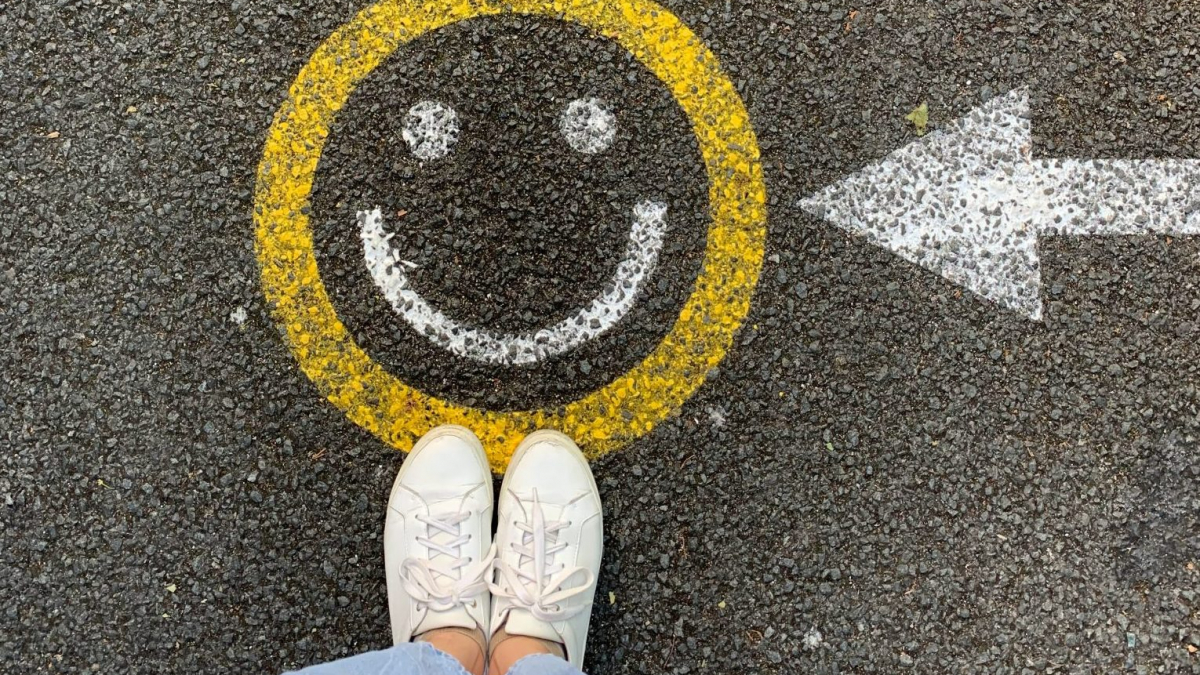 Girl standing on painted yellow smiley face with arrow pointing to the smiley face