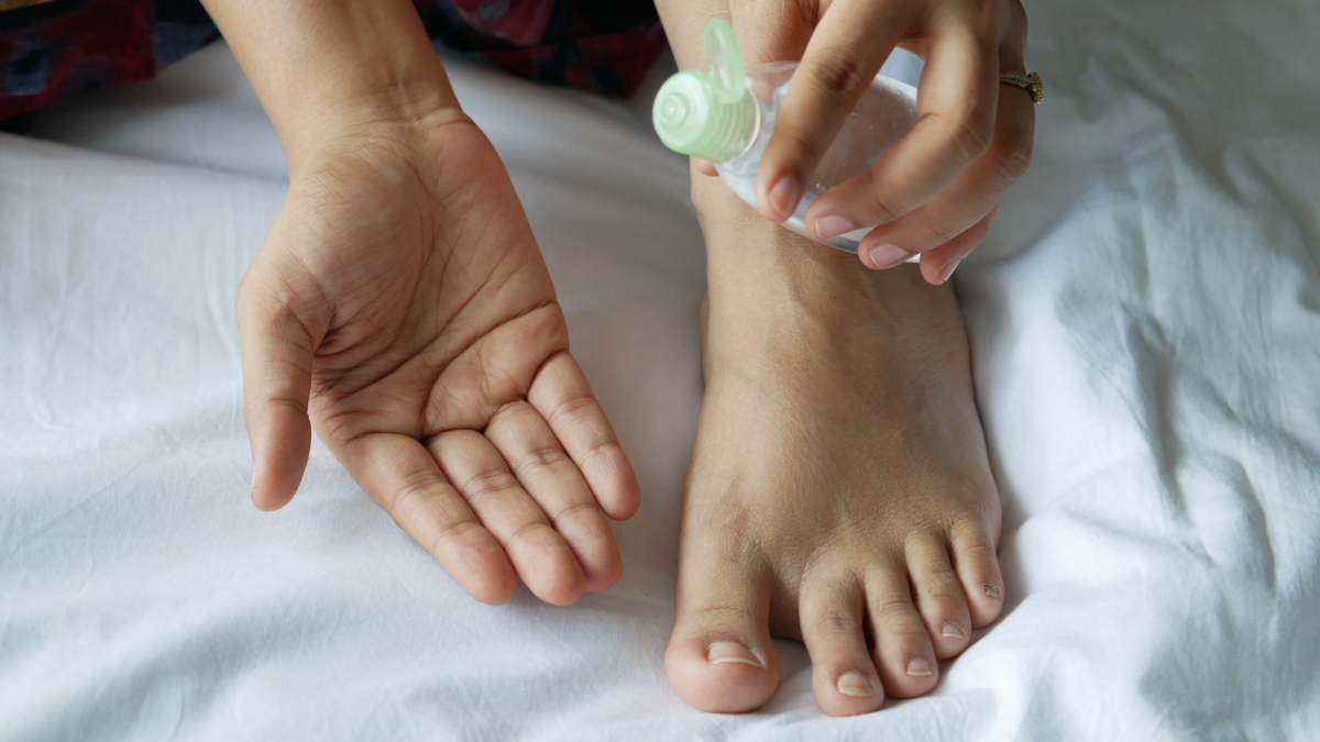 Woman holding massage oil beside foot